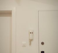 White entrance hallway in a 4-room apartment with a phone and doors.
