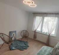 A room in a 4-room apartment with a wooden decor floor, armchairs, and lighting.