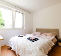 A bedroom in a 2-room apartment with a window, a bed, and a floor with a wooden decor.