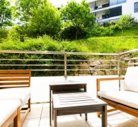 Outdoor seating on the terrace of a 2-room apartment with a view of greenery in Bratislava.