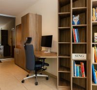 A library and a work corner with a chair in a 2-room apartment with a view of the balcony.