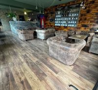 Interior of commercial spaces with comfortable seating, walls with wooden decor, and flooring with wooden decor.