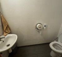 Toilet with a sink and tiles. Commercial premises with simple equipment.