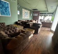 Interior of commercial spaces with comfortable sofas and wood-patterned flooring.
