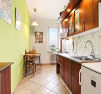A kitchen in a 2-room apartment with a wooden decor and a green wall, seating at the table.