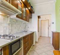 A kitchen in a 2-room apartment with a gas stove, microwave, and storage space.
