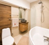 A bathroom in a family house with a corner bathtub and a sink on a wooden decor.