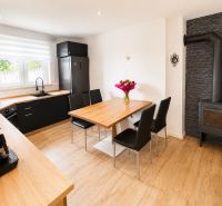 A kitchen in a family house with tiles, a wooden decor floor, and a dining table.
