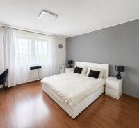 A bedroom in a family house with white furniture and a wooden decor floor.