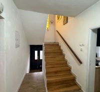A hallway in a family house with a staircase and a wooden decor floor.