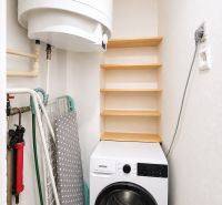 Laundry room in a family house with shelves and a washing machine.