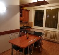A kitchen in a 3-room apartment with a wooden decor floor and a dining table.