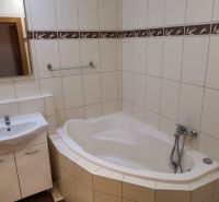Bathroom with a bathtub and a sink, light tiles in a 3-room apartment.