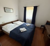 A room with a double bed, a blue blanket, and a wooden decor floor in hotels and guesthouses.