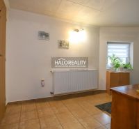 A hallway in a family house with tiles, light walls, plants, and wooden furniture.