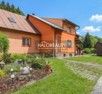 A family house in Dolná Mariková with a colorful facade surrounded by a green garden and a pathway.