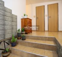 Interior of a family house with ceramic tiles, plants, and a cabinet on the stairs.