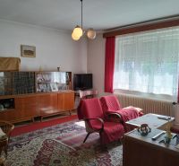Living room in a family house with red armchairs and a glass display cabinet, wooden decor flooring.