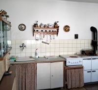 A kitchen in a family house with rustic cabinets and a classic stove.