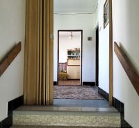 Hallway in a family house with wooden doors and tiled stairs.