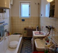 A bathroom in a family house with a bathtub, sink, and washing machine, surrounded by tiles.