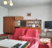 Living room in a family house with carpets, armchairs, and a television.