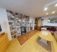 Living room with a tiled stove, sofa, and wooden decor flooring in a family house.