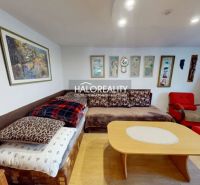 Living room in a family house with a sofa, armchairs, and paintings on the walls, floor with wooden decor.
