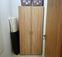 A storage cabinet with a wood decor and flowers on the boxes in a studio apartment.