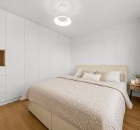 A bright bedroom with a bed, built-in wardrobes, and a wooden decor floor in a 3-room apartment.