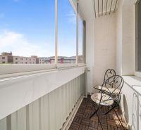 Glazed balcony with wooden floor decor in a 3-room apartment with a table and chairs.