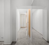 A hallway in a 3-room apartment with a large mirror, light-colored walls, and tiles.