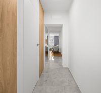 A hallway with white walls and a wooden decor floor in a 3-room apartment.