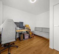 A study with a computer, guitars, a gray chair, and a wooden decor floor in a 3-room apartment.
