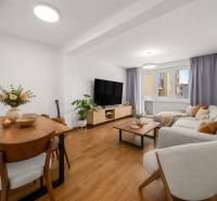 Living room in a 3-room apartment with a wooden decor floor, light furniture, and decorations.