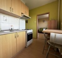 A kitchen in a studio apartment with a wooden decor floor, dining table, and equipment.
