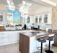 A kitchen in a family house with white cabinets, a coffee counter, and a clock on the wall.