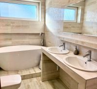 A bathroom in a family house with a bathtub, shower, and sink with storage space.