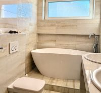 A bathroom in a family house with a bathtub, toilet, and double sink.