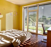 Children's room with unicorns, a large window, and a wooden decor floor in a family house.