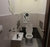 Bathroom in a 2-room apartment with a toilet, sink, and light tiles.
