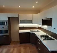 A kitchen in a 2-room apartment with a wood-decor floor and built-in appliances.