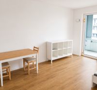 Living room in a studio apartment with a wood-patterned floor and a dining table.