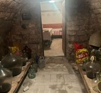 A traditional stone cellar in a cottage with shelves and demijohns.