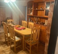 Dining area in a cabin with a wooden table and chairs, illuminated by a chandelier.
