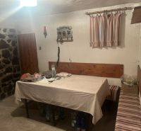 Dining nook with a tablecloth, bench, and stone on the wall in a cabin.