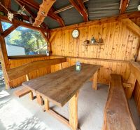 A wooden cabin with a massive table and benches offers a cozy seating area.