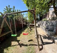 Wooden swings in the yard of the cottage in Kunovo, Senica, with a terraced garden layout.