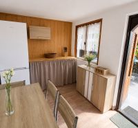 A kitchen in a cottage with a wooden decor floor, a table, and white flowers.