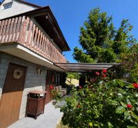 A cottage in Kunov near Senica surrounded by greenery and flowers with wooden elements.